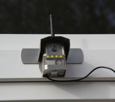 Na jasnej ścianie budynku zaczepiony sensor z antenkami