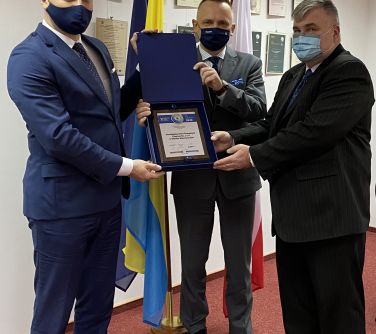 Burmistrz i prezes PEC odbierają nagrodę od przedstawiciela organizatora konkursu