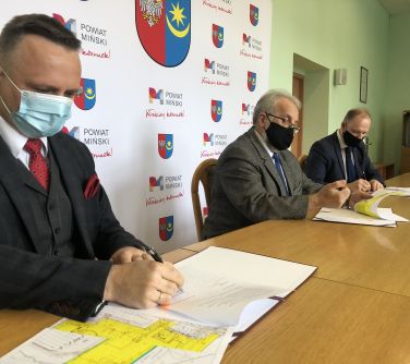 burmistrz maista podpisuje list intencyjny w tle starosta i wicestarsta miński