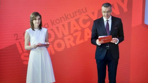 Podsumowanie ogólnopolskiego konkursu „Innowacyjny Samorząd”. Konferansjerzy: kobieta w białej sukience i mężczyzna w...