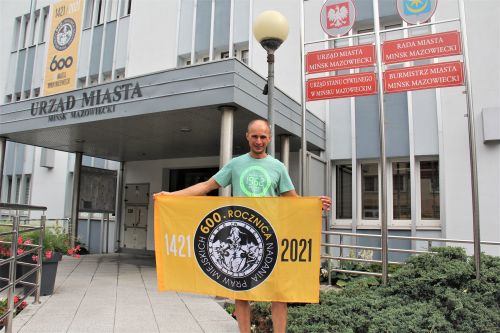 Sebastian Reczek przed Urzędem Miasta z flagą 600-lecia