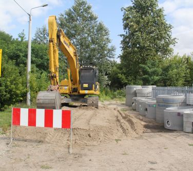 ul. Dźwigowa. Teren rozpoczętej inwestycji drogowej. W tle koparka i elementy do budowy drogi.