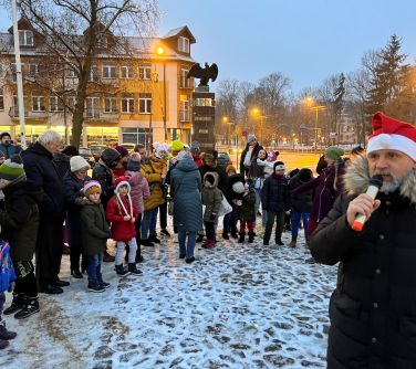 Burmistrz miasta przemawia do zgromadzonych na Starym Rynku dzieci podczas Mikołajek Miejskich.
