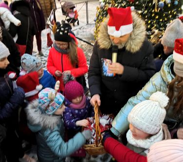 Burmistrz miasta rozdaje dzieciom słodkie upominki.