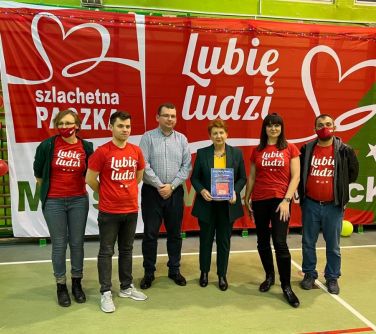 Wolontariusze akcji Świąteczna Paczka wspólnie z Teresą Wargocką w tle napis Lubię ludzi.