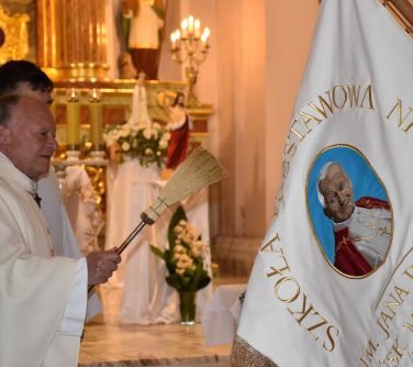 Wnętrze kościoła. Ksiądz święci sztandar