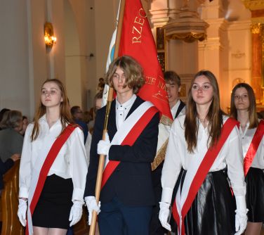 Wnętrze kościola. Dzieci na galowo stoją ze sztandarem