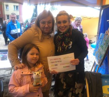 Pochmurny dzień. Dwie kobiety i dziecko pozują do zdjęcia pod namiotem