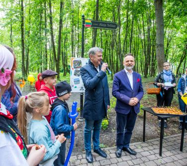 Park za dnia. Przy alejce mężczyzna przemawia