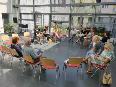 w kole ustawione krzesła, na któych siedzą osoby, rozmowa