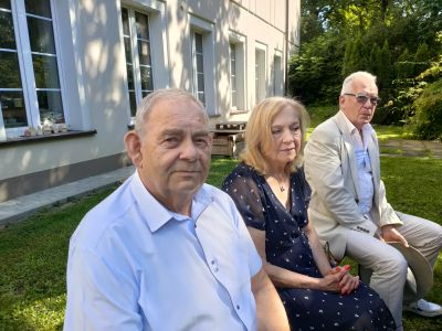 dwóch mężćzyzn siedzących pomiędzy nimi kobieta
