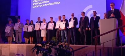 osoby stoją obok siebie na scenie z nagrodami w ręku