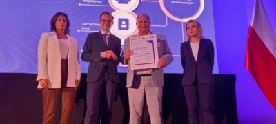 cztery osoby stoją obok siebie na scenie w nagrodami w ręku