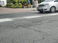Widok nawierzchni ulicy, nadjeżdżający samochód z prawej strony