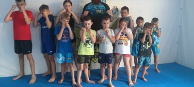Dzieci w wieku ok. 10 lat w strojach sportowych pozują do zdjęcia z trenerem