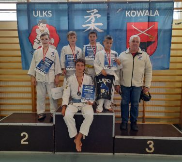 zawodnicy judo z trenerem na podium