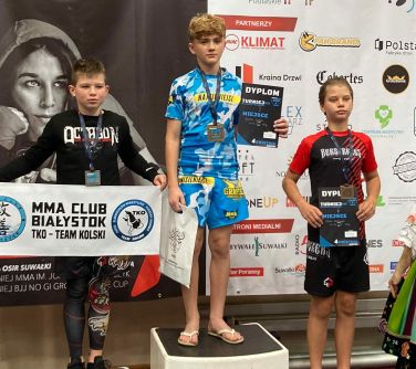 trzech zawodników MMA stoi na podium
