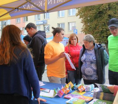 ludzie przy namiocie, rozmawiają z wystawcami