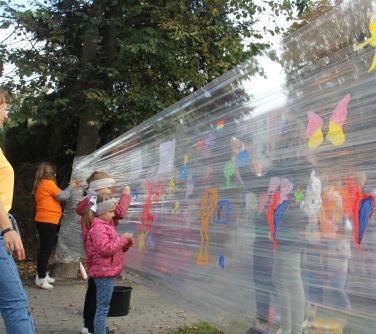 dziewczynki malujące na folii rozciągmiętej między drzewami