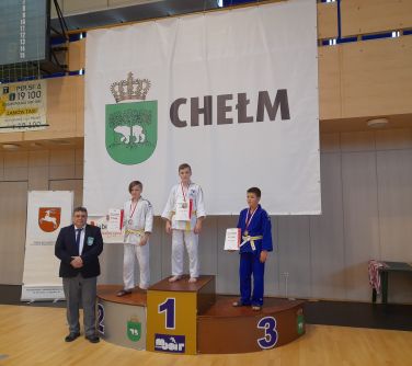 młodzi zawodnicy judo na podium, w tle baner z napisem "Chełm"