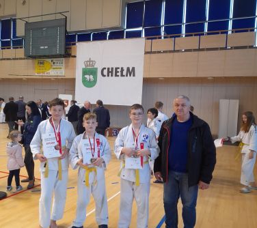 trzech zawodników judo pozuje do zdjęcia z trenerem