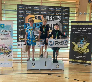 trzech zawodników pozuje do zdjęcia na podium w towarzystwie mężczyzny