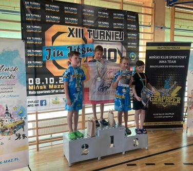 uśmiechnięci zawodnicy stoją na podium