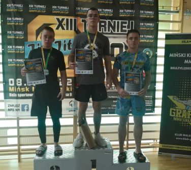 trzech zawodników pozuje do zdjęcia na podium