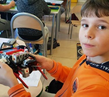 Uczeń pokazuje zbudowanego przez siebie robota