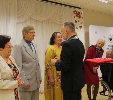 burmistrz miasta wręcza medal mężczyźnie w szarym garniturze