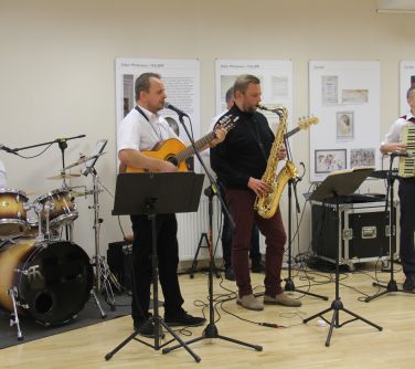 mężczyzna śpiewa, gra na gitarze z zespołem