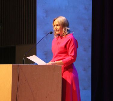 kobieta stojąca przy mównicy przemawia do publiczności