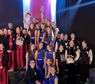 liczna grupa tancerzy pozuje do zdjęcia na podium