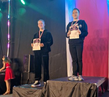 dwóch chłopców z dyplmami stoi na podium