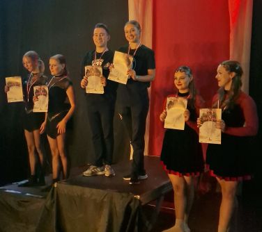 tancerze z dyplomami w rękach stoją na podium