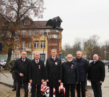 władze lokalne pozują do zdjęcia przy pomniku niepodległości