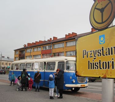 na pierwszym planie przystanek z napisem "przystanek historia" w tle autobus "ogórek"