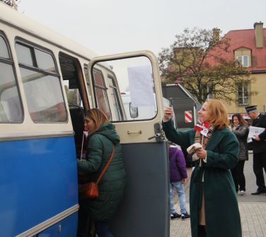 kobieta robi zdjecie pasażerom autobusu historycznego