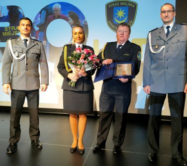 komendant straży pozuje do zdjecia z przedstawicielami policji