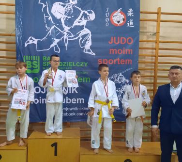 chłopcy w komonach stoją na podium