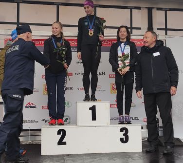 dzięwczęta stoją na podium, mężczyzni skłądają im gratulacje