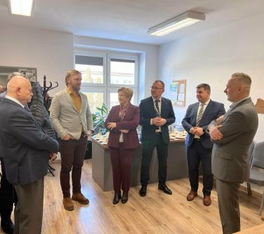 osoby stoją, rozmawiają z tytłu na biurku poczęstunek na talerzach