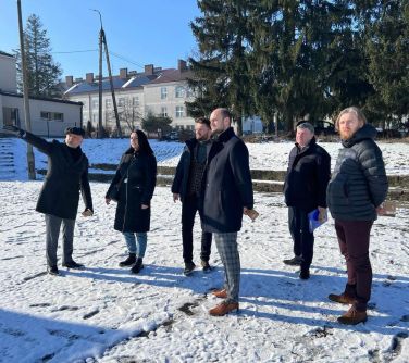 sześć osób stoi na boisku pokrytym sniegiem, mężczyzna wskazuje kierunek dłonią