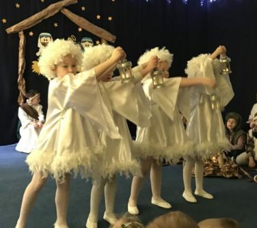 czwórka dzieci w przebraniach aniołków trzyma lampy w rękach