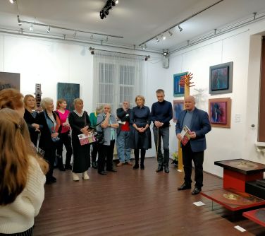 osoby stoją w półkolu na białych ścianach wisza obrzy