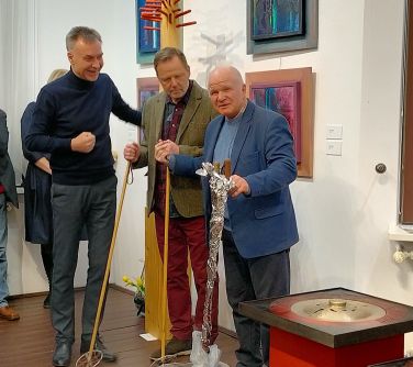 trzech mężczyzn stoi dwóch z nich trzyma kijki w dloniach