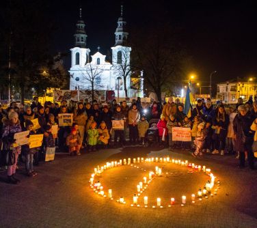 osoby stoją, spiewaja naokoło zapalonych świec