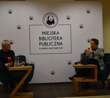 dwóch mężczyzn siedzi w fotelach przemawiają