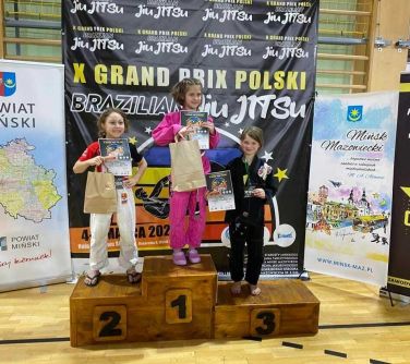 trzy dziewczynki stoją na podium