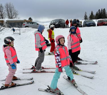 grupa dzieci stoi na nartach